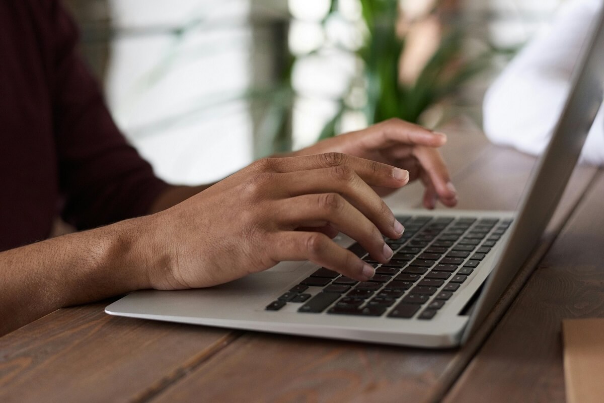 a laptop keyboard with hands typing